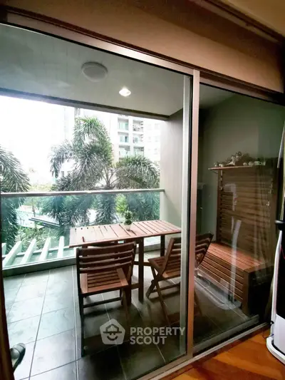 Charming balcony with wooden furniture and lush greenery view in modern apartment.