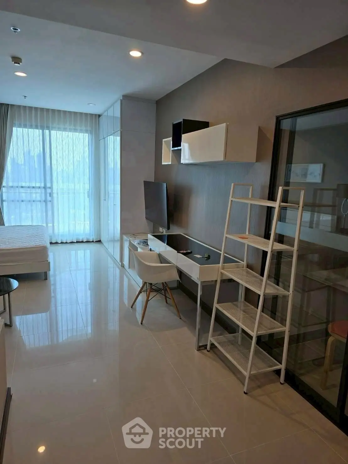Modern studio apartment with sleek furnishings and large windows for natural light.