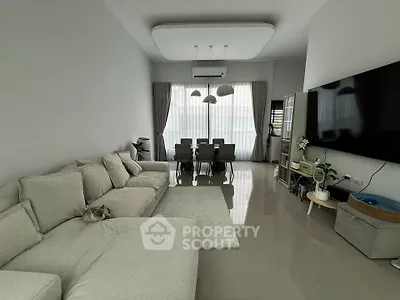 Spacious modern living room with large sofa and dining area, featuring sleek design and ample natural light.