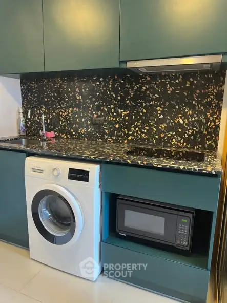 Modern kitchen with washing machine, microwave, and stylish backsplash