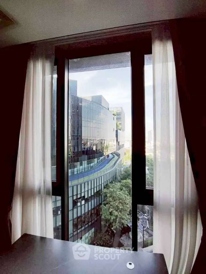Modern city view from a high-rise window with sleek architecture and lush greenery.