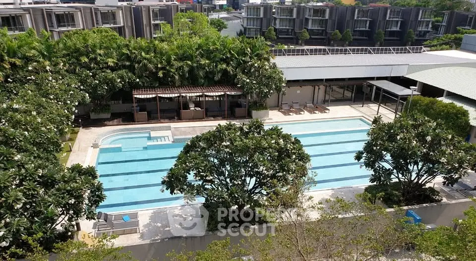 Luxurious residential complex with a pristine swimming pool surrounded by lush greenery.