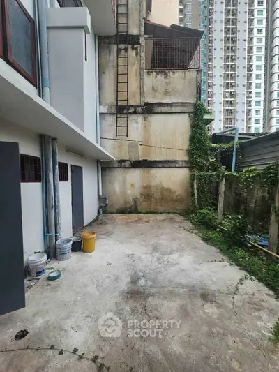 Urban outdoor space with concrete flooring and high-rise building backdrop, ideal for creative renovation.