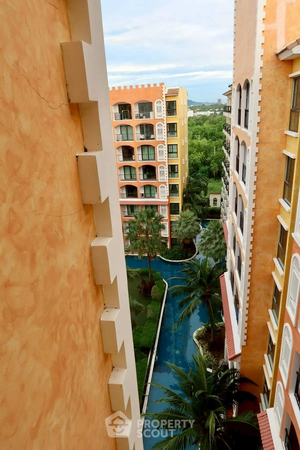 Stunning view of a modern apartment complex with lush greenery and a winding pool.
