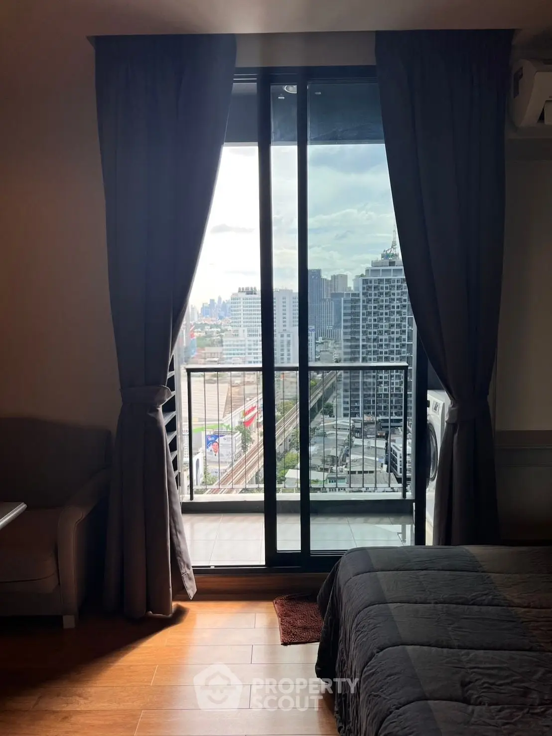 Modern bedroom with balcony offering stunning city view and natural light.