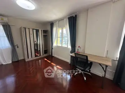 Spacious bedroom with wooden flooring, modern wardrobe, and study desk with chair, ideal for comfortable living.