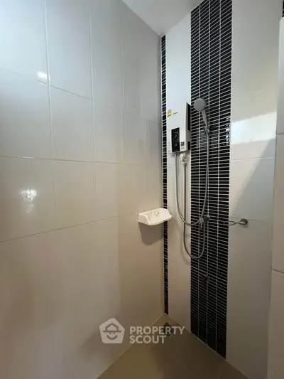Modern bathroom with sleek shower design and stylish black and white tiles.