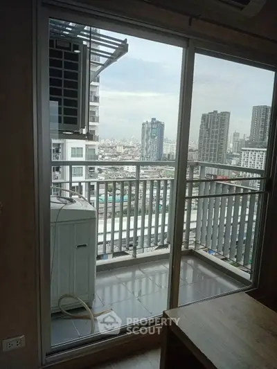 High-rise apartment balcony with city skyline view through glass doors.
