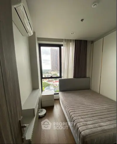 Cozy bedroom with city view, featuring a modern bed and air conditioning, perfect for urban living.