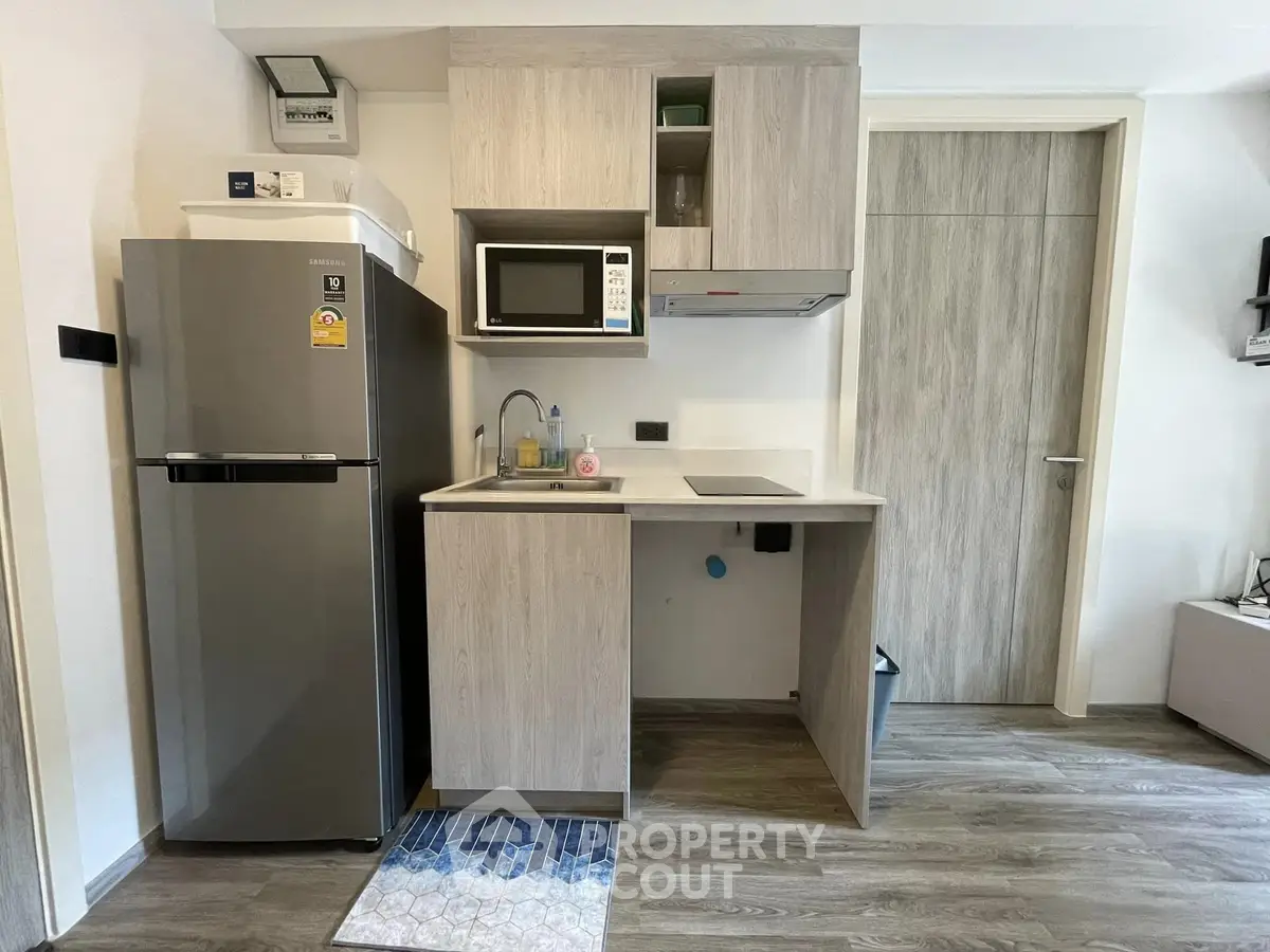 Modern compact kitchen with sleek appliances and stylish cabinetry in a cozy apartment setting.
