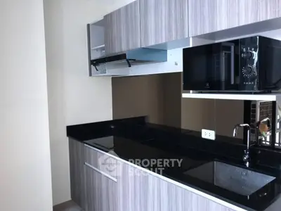 Modern kitchen with sleek black countertops and built-in microwave