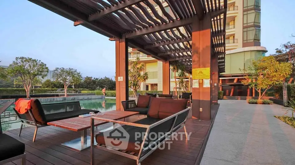 Luxurious outdoor seating area by the pool with modern furniture and lush greenery.