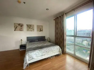 Spacious bedroom with large window offering city view, wooden flooring, and modern decor.