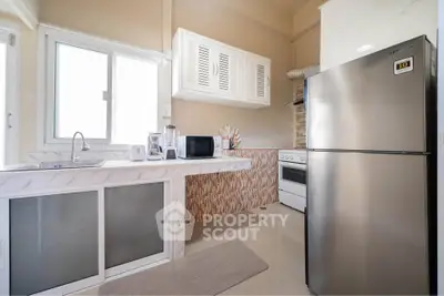 Modern kitchen with stainless steel fridge and sleek countertops in a bright, airy space.