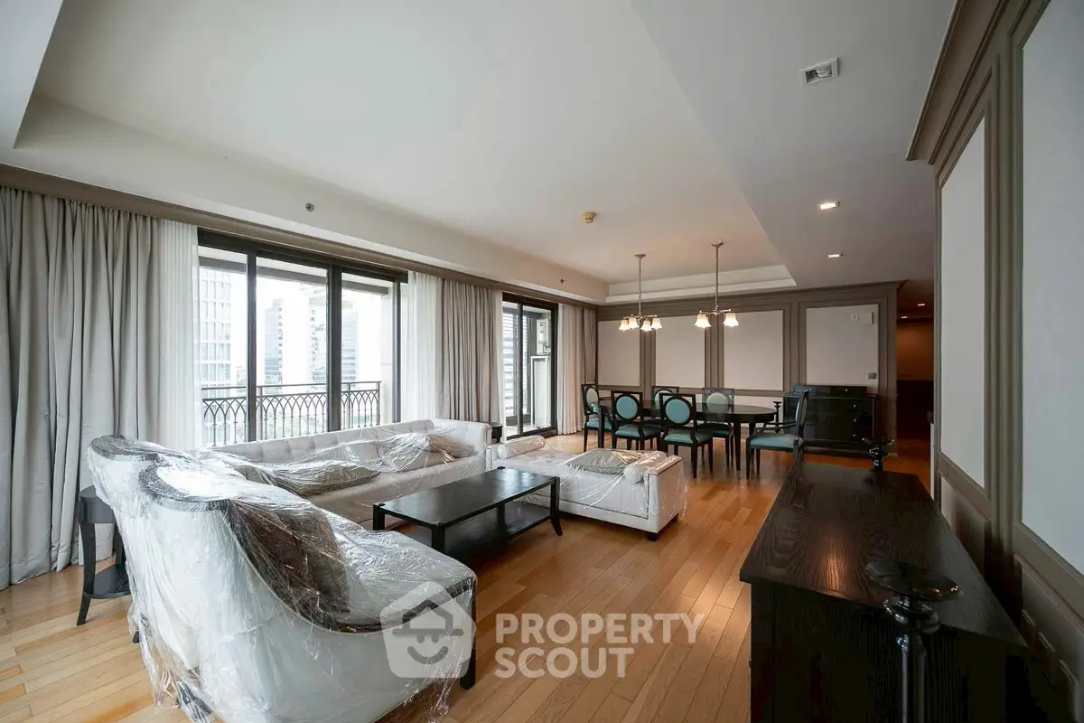 Spacious living room with elegant furniture and large windows offering city views.