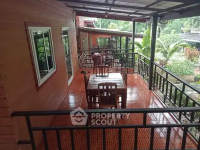 Charming wooden balcony with outdoor dining set and lush garden view
