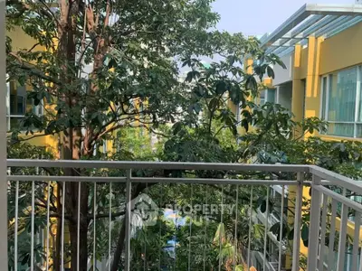 Charming balcony view overlooking lush greenery and modern building facade, perfect for nature lovers.