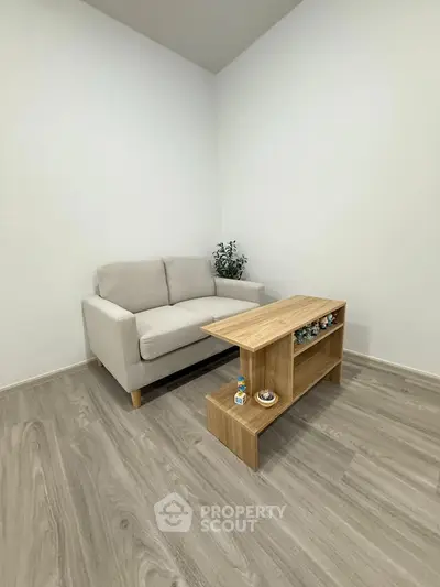Minimalist living room with cozy sofa and modern wooden coffee table on sleek flooring.