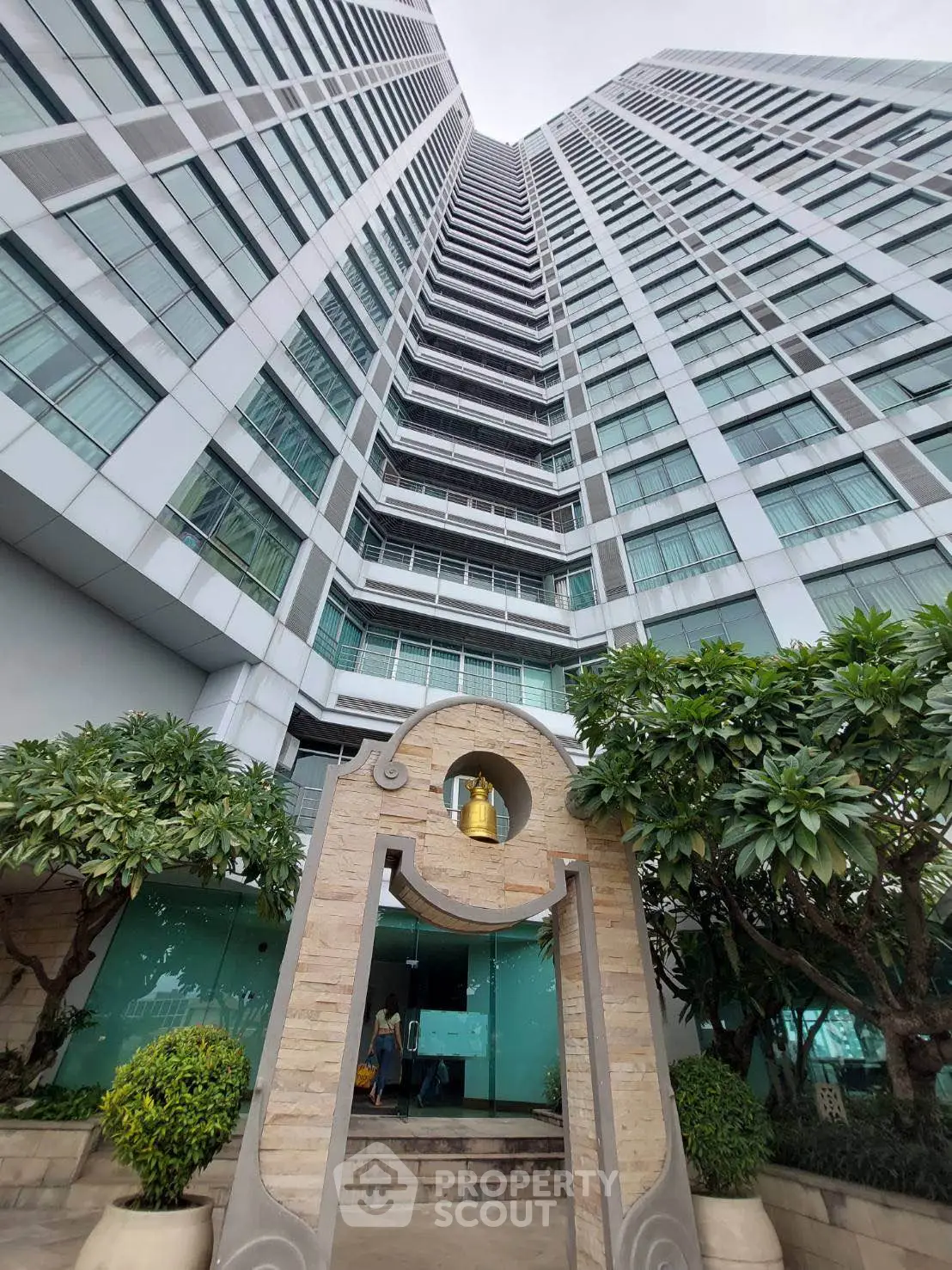 Stunning high-rise building with modern architecture and lush greenery at the entrance.