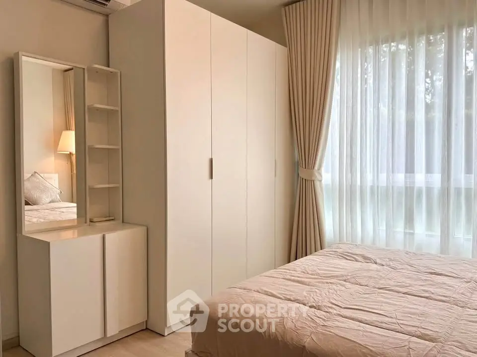 Cozy bedroom with natural light, featuring a wardrobe and elegant curtains, perfect for a serene retreat.