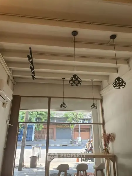 Chic modern interior with stylish pendant lights and large windows offering street view.