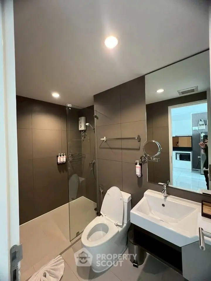 Modern bathroom with sleek design, featuring a glass shower enclosure and contemporary fixtures.