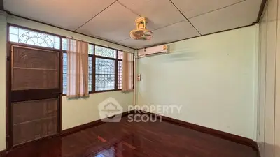 Spacious empty room with wooden flooring and large windows
