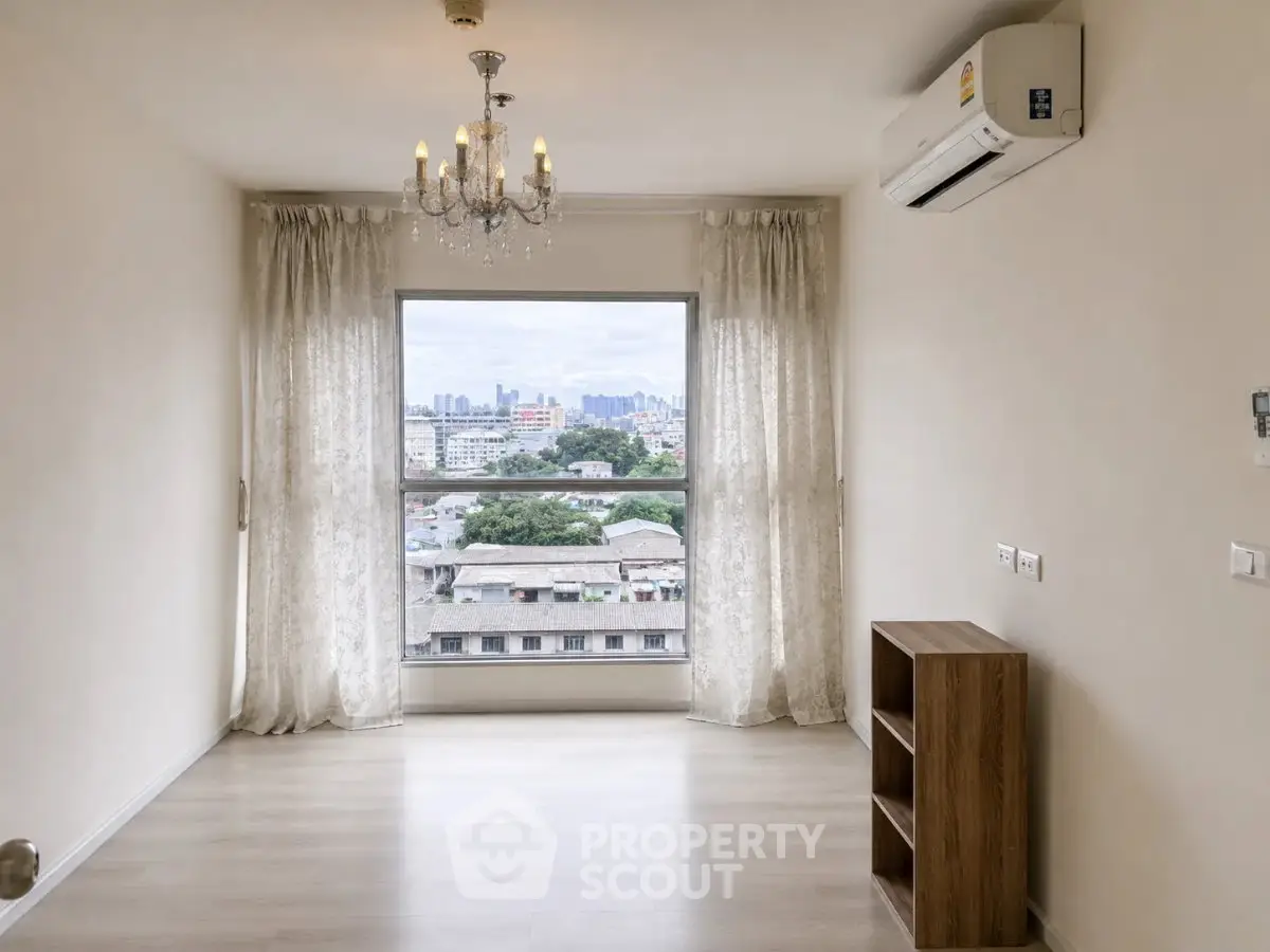 Bright living room with chandelier and city view through large window.