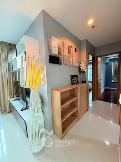 Modern apartment interior with stylish decor and open layout, featuring sleek shelving and elegant lighting.