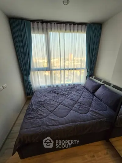 Cozy bedroom with large window offering stunning city views, featuring elegant curtains and a comfortable bed.