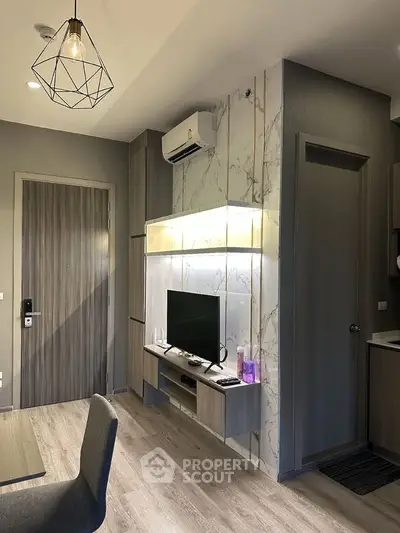 Modern living room with stylish decor and air conditioning, featuring a sleek TV setup and elegant lighting.