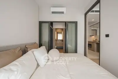 Modern bedroom with ensuite bathroom and sleek kitchen view, featuring neutral tones and contemporary design.
