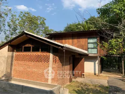 Charming rustic house with brick and wood exterior surrounded by lush greenery, perfect for nature lovers.