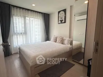 Modern bedroom with large window, stylish decor, and ample natural light in a contemporary apartment.