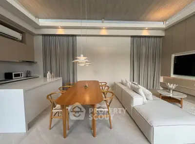 Modern open-plan living room with sleek kitchen and stylish dining area, featuring elegant lighting and contemporary furniture.
