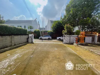 Spacious residential driveway with parked cars and lush greenery