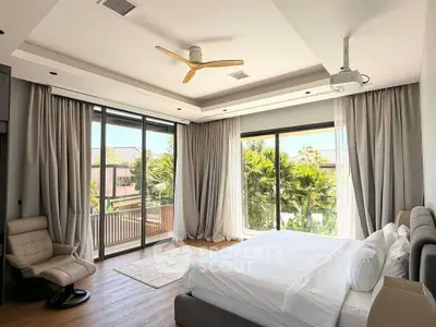 Luxurious bedroom with large windows and balcony overlooking lush greenery, featuring modern decor and ceiling fan.