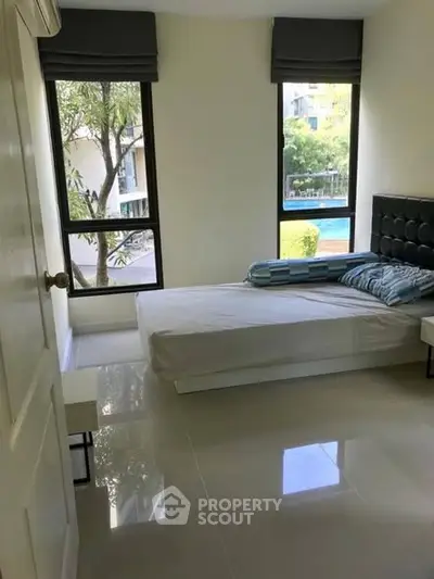 Bright bedroom with large windows and pool view in modern apartment