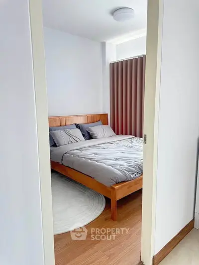 Cozy bedroom with wooden bed frame and modern decor, perfect for relaxation.