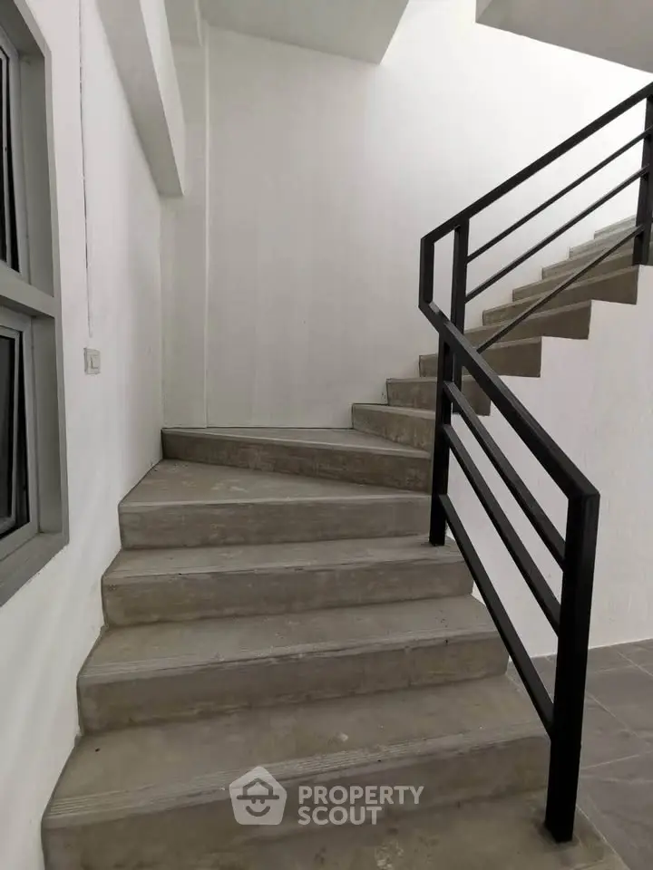 Modern staircase with sleek metal railing in a minimalist building interior.
