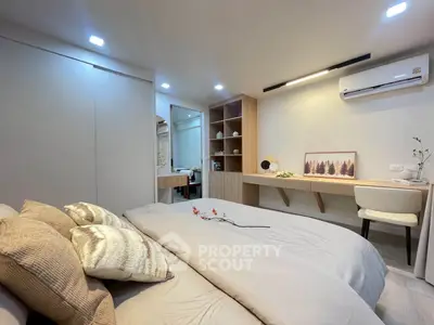 Modern bedroom with stylish decor and workspace, featuring cozy bedding and elegant lighting.