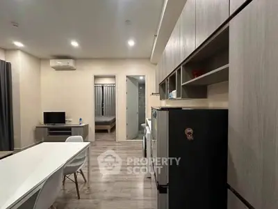 Modern open-plan living room with sleek kitchen and dining area, featuring contemporary furniture and appliances.
