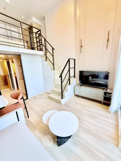 Modern loft-style living room with high ceilings and stylish staircase