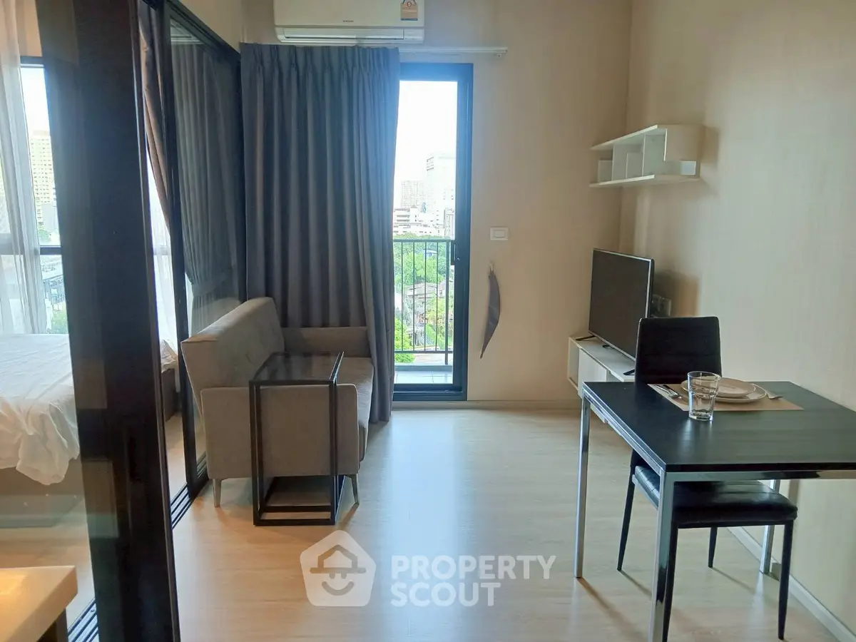 Modern studio apartment with balcony and city view, featuring sleek furniture and natural light.