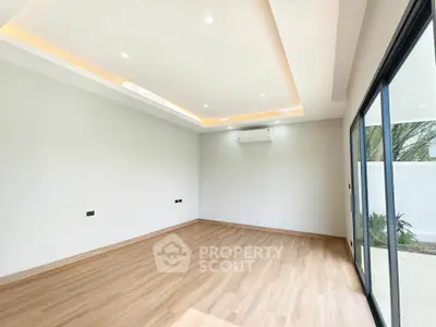 Spacious modern living room with wooden flooring and large sliding glass doors.