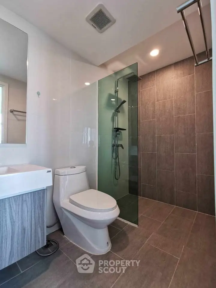 Modern bathroom with glass shower and sleek fixtures in contemporary apartment.