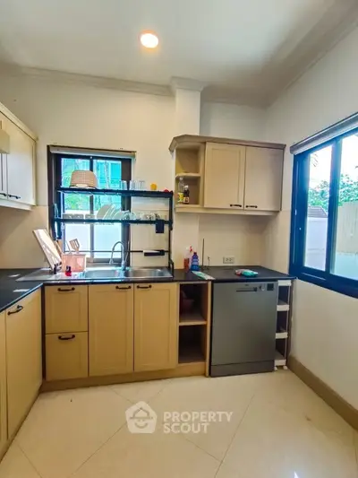 Modern kitchen with beige cabinets and stainless steel dishwasher in a bright, airy space.