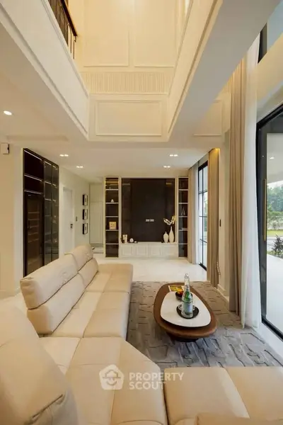 Luxurious modern living room with high ceilings and elegant decor, featuring large windows and plush seating.