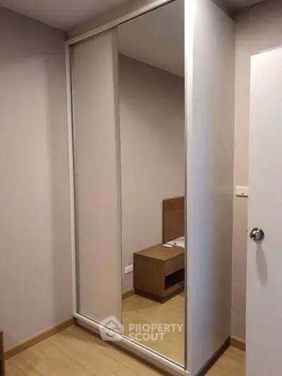 Modern bedroom with sleek mirrored wardrobe and wooden flooring