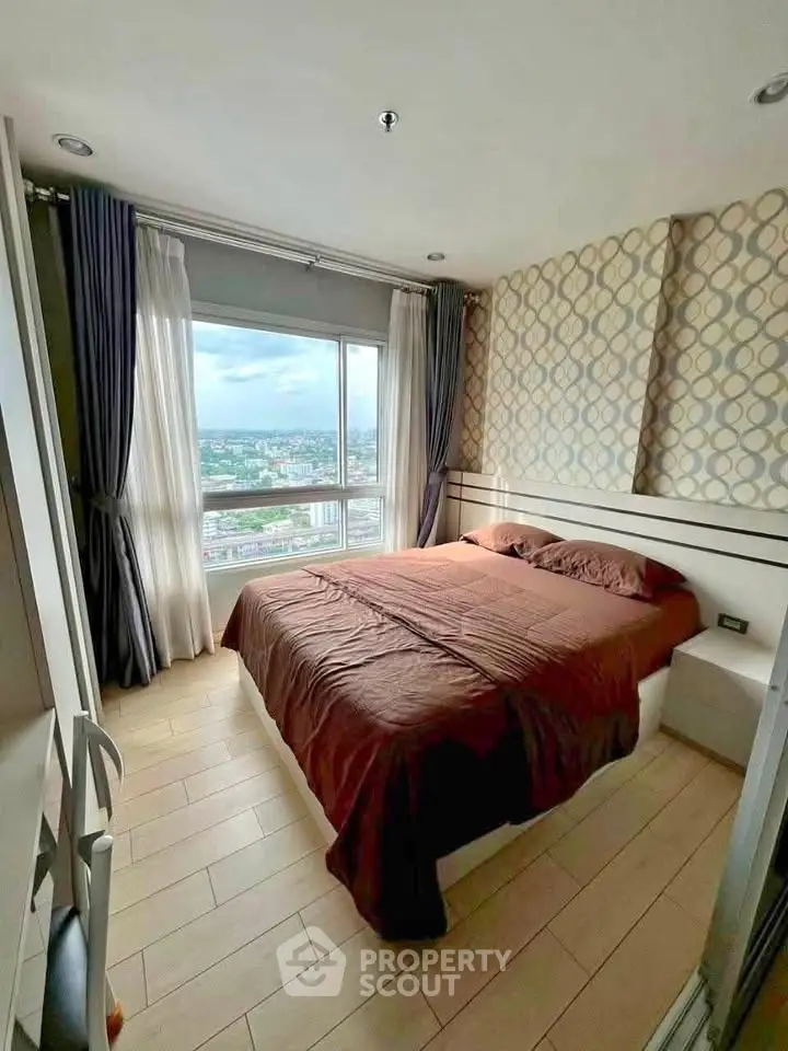 Cozy bedroom with city view, featuring modern decor and large window for natural light.